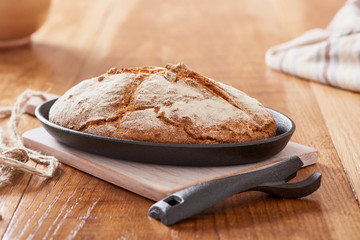 soda bread  on a oval cast iron pan over a wooden table