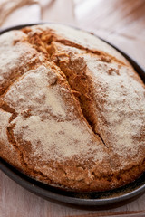 soda bread  on a oval cast iron pan over a wooden table