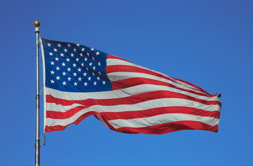 Flag of United States of America waving on the wind on blue sky