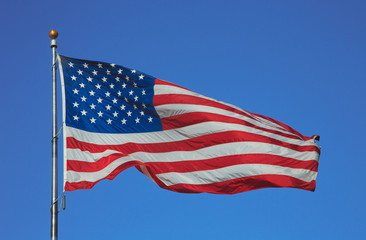Obraz premium Flag of United States of America waving on the wind on blue sky