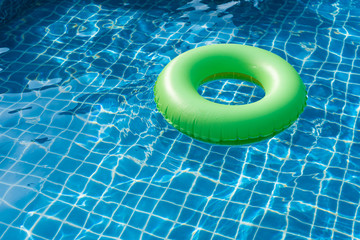 Green pool float, ring floating in a refreshing blue swimming pool