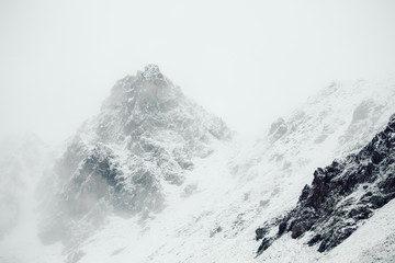 Mountain peak full of snow surround by clouds in the Alps. Film filter added