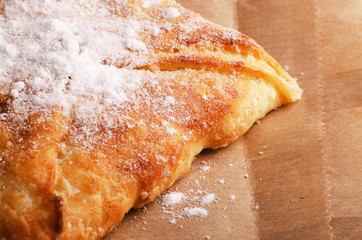 Fresh bun with powdered sugar on a packing paper