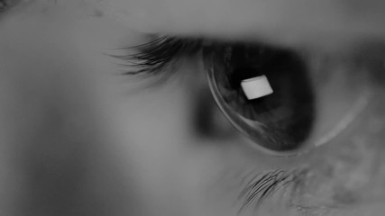 macro view of young woman eye without cosmetics looks at the computer during working in the evening, the monitor reflects in her eyes