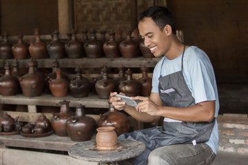 male potter taking picture of his product in pottery workshop