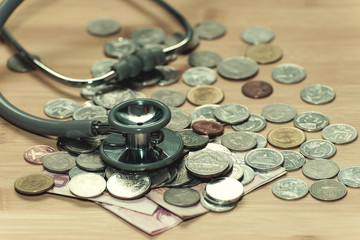 Concept of expensive healthcare with coins, bills, and stethoscope