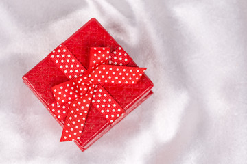 Flat lay red gift box with bow over white satin