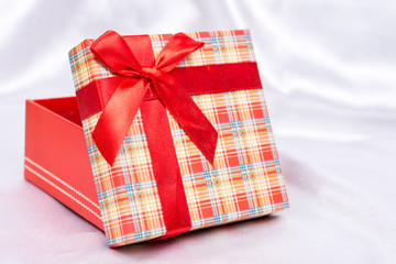 Gift box with red bow over white satin