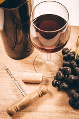 Glass of red wine with a sprig of grapes on a wooden table.