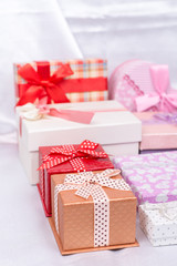 Pile of gift boxes with bows over white satin