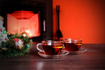 Cup with Christmas ornament near fireplace. Winter holiday concept