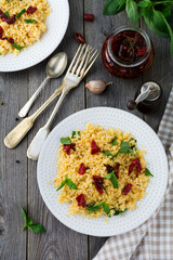 Bulgur with dried tomatoes and basil on an old wooden background. Vegetarian dish.Rustic style. Selective focus.Top view.