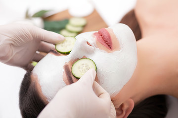Spa concept. Young woman with nutrient facial mask in beauty salon, close up
