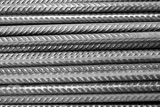 closeup of a stack of rusty metal deformed reinforcement bars / steel rods from a construction site  (black and white version)
