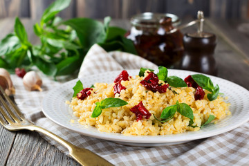 Bulgur with dried tomatoes and basil on an old wooden background. Vegetarian dish.Rustic style. Selective focus.