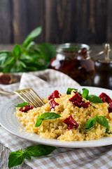Bulgur with dried tomatoes and basil on an old wooden background. Vegetarian dish.Rustic style. Selective focus.