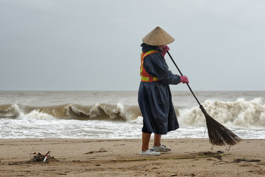 worker cleaning a beach in the rainy season.