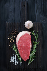 Raw fresh beef medallion steak on a black wooden cutting board