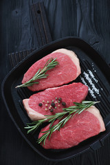 Cast-iron grill pan with raw fresh beef medallions, top view