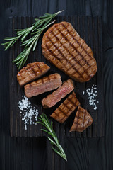 Pair of bbq beef medallions on a black wooden background