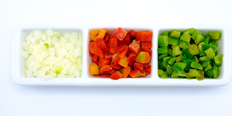 Red and green pepper and onion cut into dice in a bowl