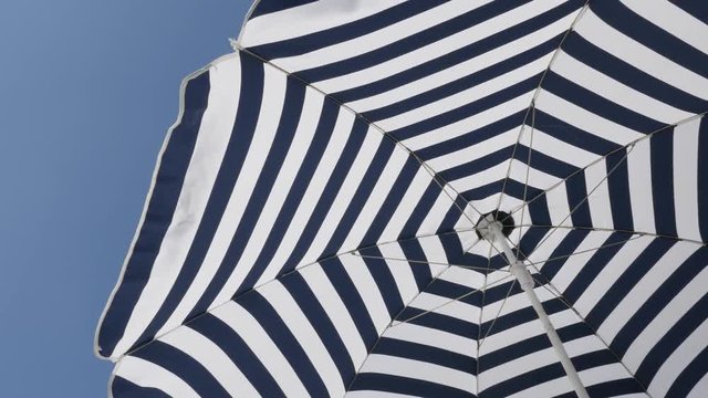 Striped umbrella sun protection fabric moving on the wind 4K 2160p 30fps UltraHD footage - Blue and white beach parasol with hypnotic effect 3840X2160 UHD video 