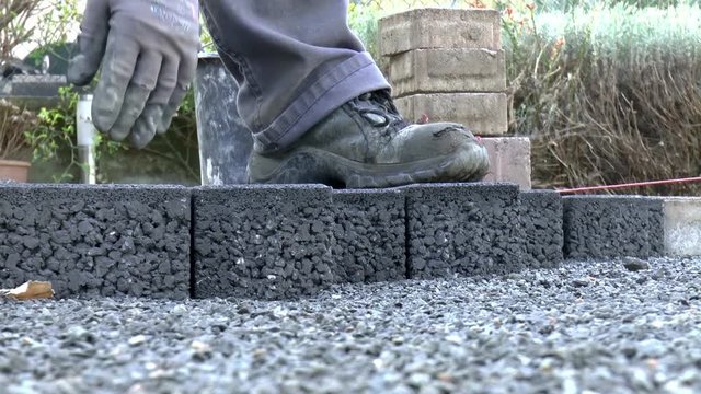 Bauarbeiter verlegt Pflastersteine
(Construction worker laying pavement rocks)