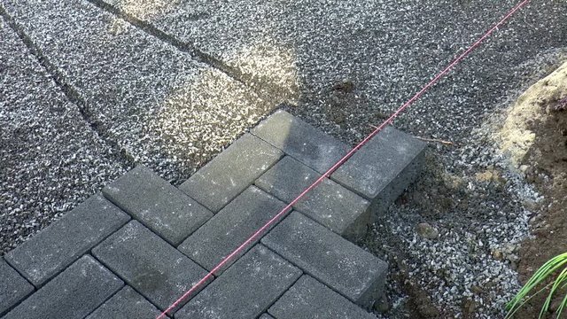 Bauarbeiter verlegt Pflastersteine
(Construction worker laying pavement rocks)