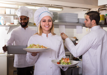 Crew of professional cooks working at restaurant