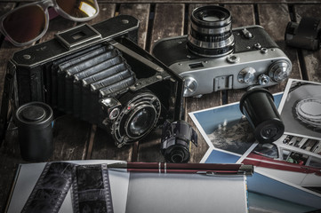 Fototapeta na wymiar Retro Fotokameras auf einem Tisch / Alte Retro Fotoapparate auf einem Tisch mit Fotografien, Negativen und Filme mit Textfreiraum.