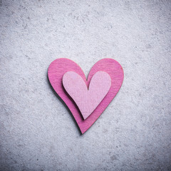 Obraz premium Valentines Day background with decorative pink wooden heart on concrete stone with copy space for text. Valentine's Day concept. View from above.