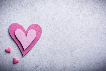 Obraz premium Valentines Day background with decorative pink wooden heart on concrete stone with copy space for text. Valentine's Day concept. View from above.