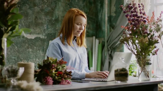 smiling florist typing on laptop