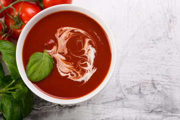 Tomato soup with basilic, cherry tomatoes on white background Top view