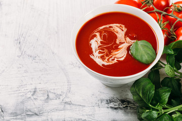 Tomato soup with basilic, cherry tomatoes on white background Top view
