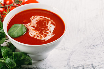 Tomato soup with basilic, cherry tomatoes on white background Top view