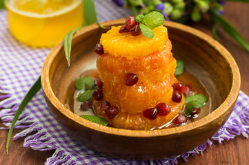 Dessert of fruits watered honey with mint leaves. Wooden background. Close-up