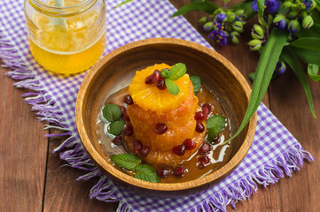 Dessert of fruits watered honey with mint leaves. Wooden background. Close-up