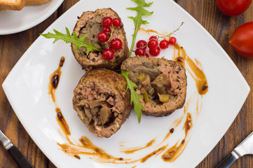 Meatloaf stuffed with mushrooms  sauce and berries. Wooden rustic background. Top view. Close-up