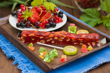 Churchkhela Georgian national delicacy, with different sweets and berries on a background of flowers. Wooden table. Close-up