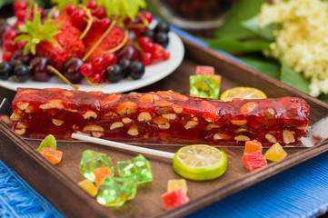 Churchkhela Georgian national delicacy, with different sweets and berries on a background of flowers. Wooden table. Close-up