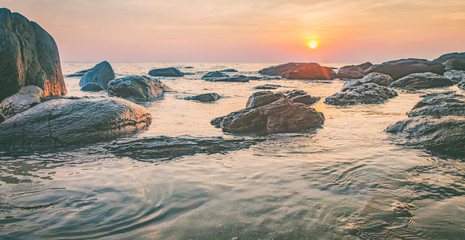 Tropical colourful sunset on the beach, Koh Chang island,Thailand. Panorama view of dark night sea with protruding stones