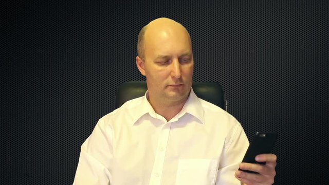 A man looks at the phone on sota background.