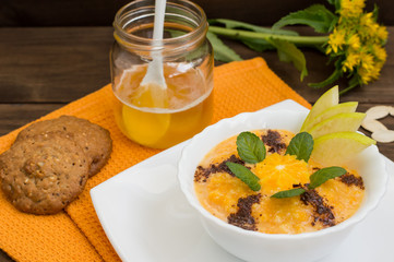 Pumpkin, wheat porridge with honey, orange and mint. Wooden table. Close-up