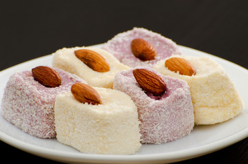 Turkish Delight with almonds on a saucer, close-up, black background