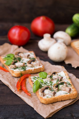 Sandwiches consisting of toast with fried grilled mushrooms and melted cheese  spices. Wooden black table. Close-up