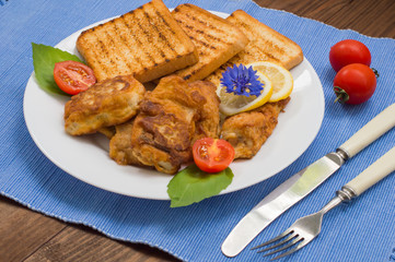Fish in batter with croutons grilled. Wooden background. Top view. Close-up