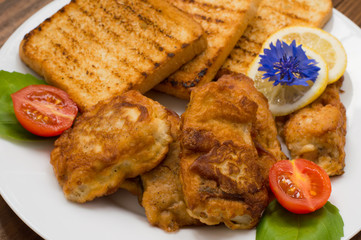 Fish in batter with croutons grilled. Wooden background. Top view. Close-up