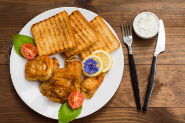 Fish in batter with croutons grilled. Wooden background. Top view. Close-up
