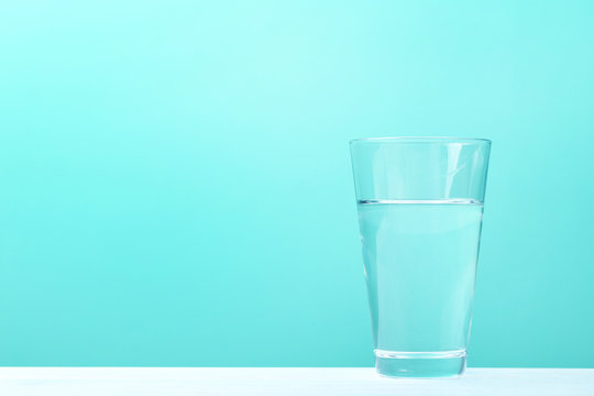 Glass with water on mint background